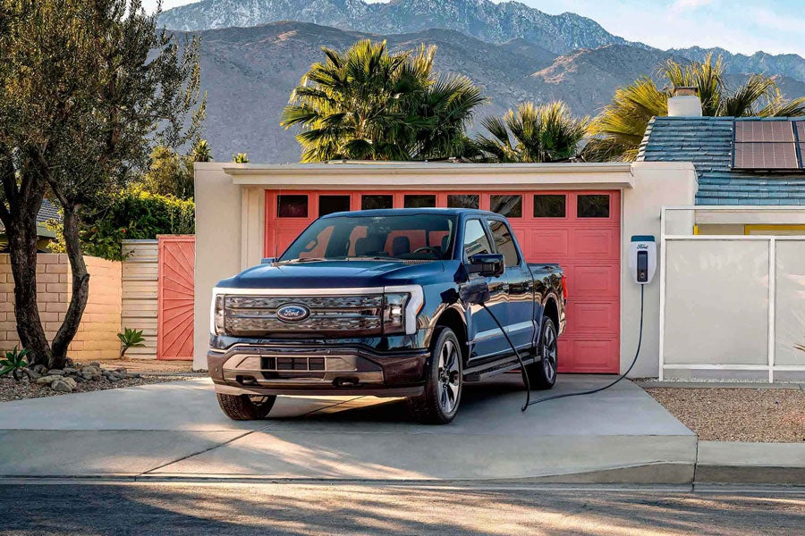 An F-150 Lightning charges in a driveway